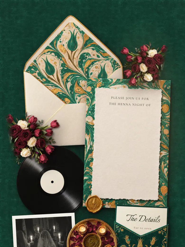 The Kına Night invitation in emerald and gold: a marbled envelope liner, crimson roses and a gilded card on emerald velvet