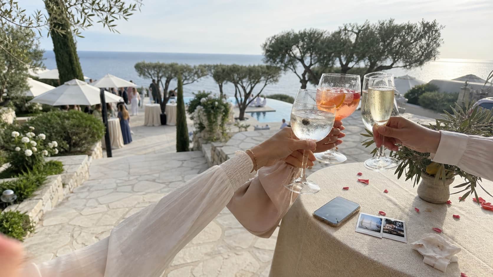 Guests making a toast at a premium coastal wedding, with a phone and printed memories on the table