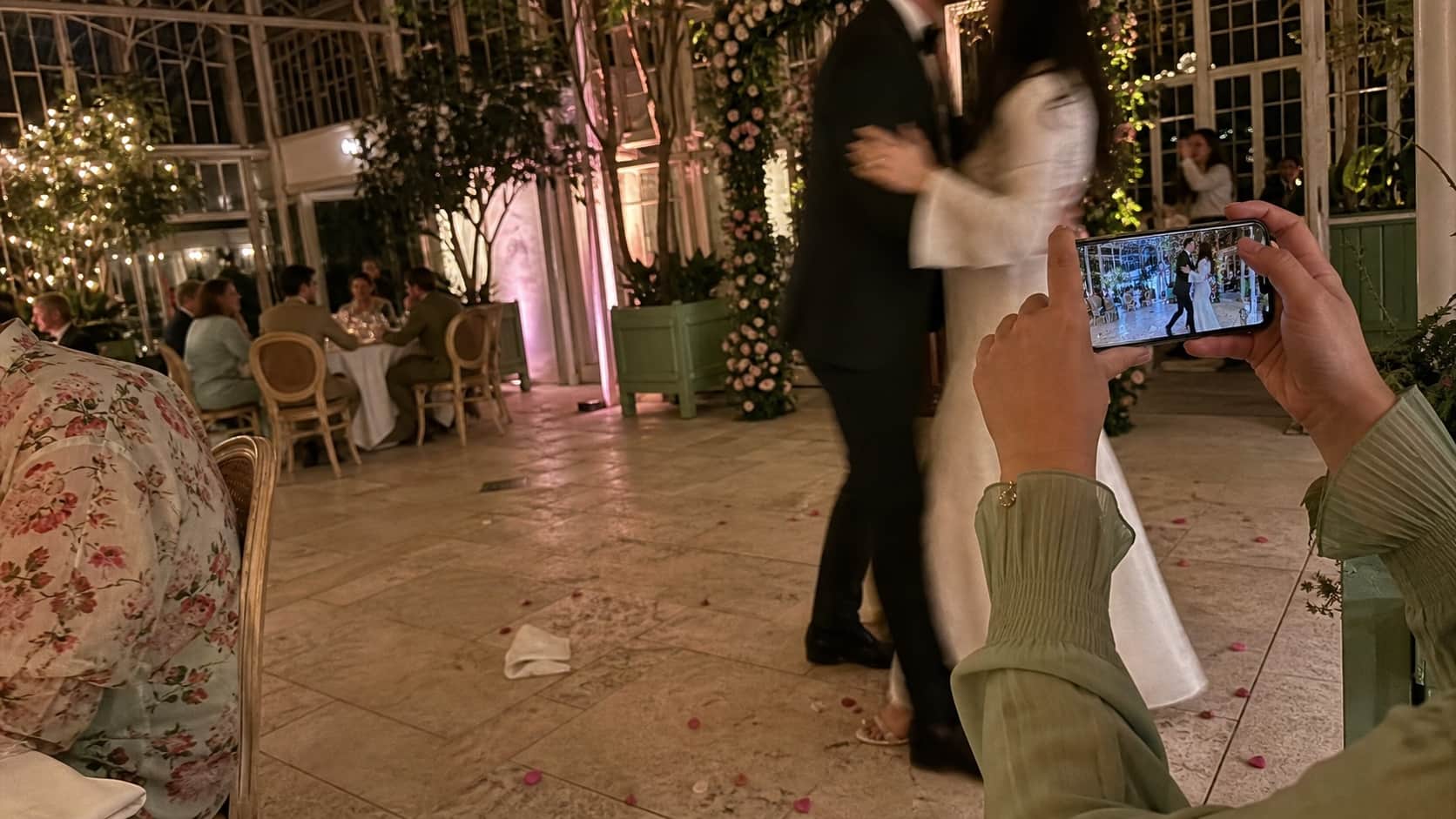 A guest taking an iPhone photo on an elegant glasshouse dance floor
