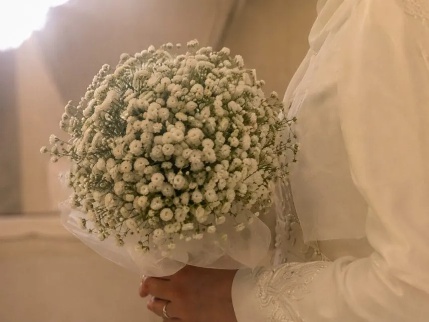 A white wedding bouquet against a long-sleeved dress