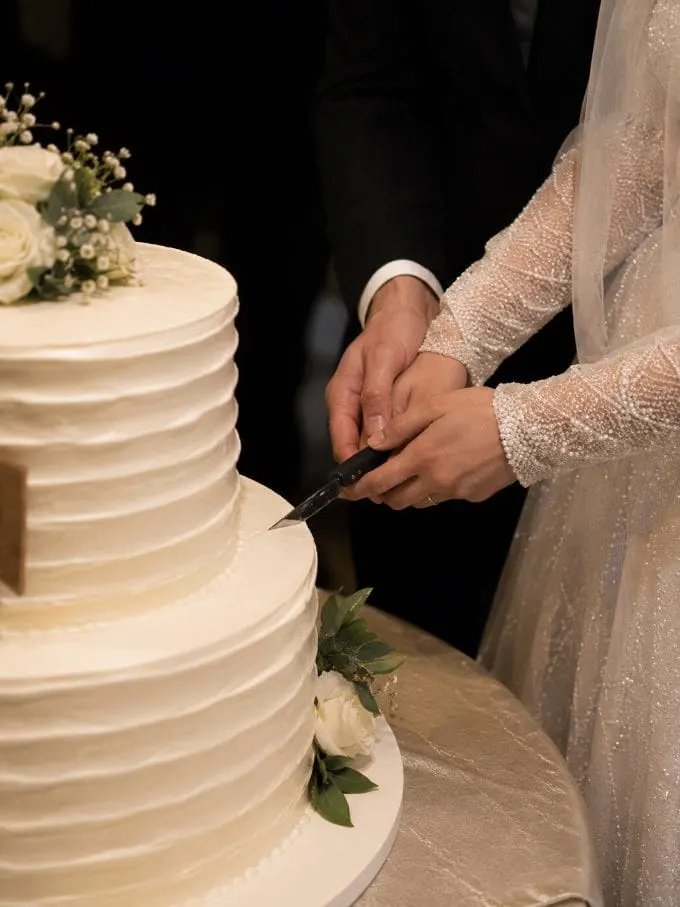 The couple’s hands cutting their wedding cake