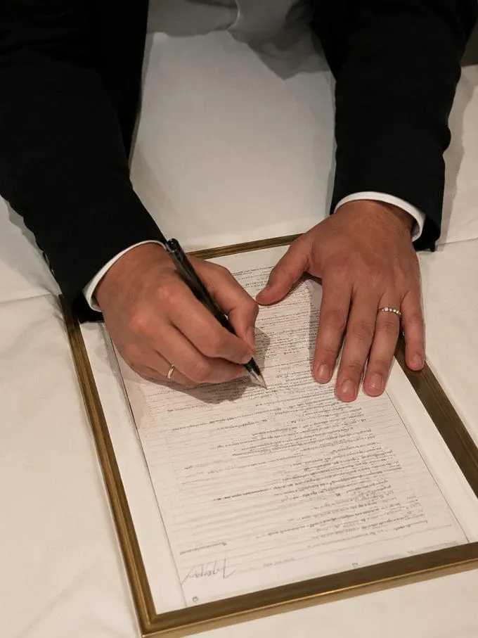 A close-up of the wedding register being signed