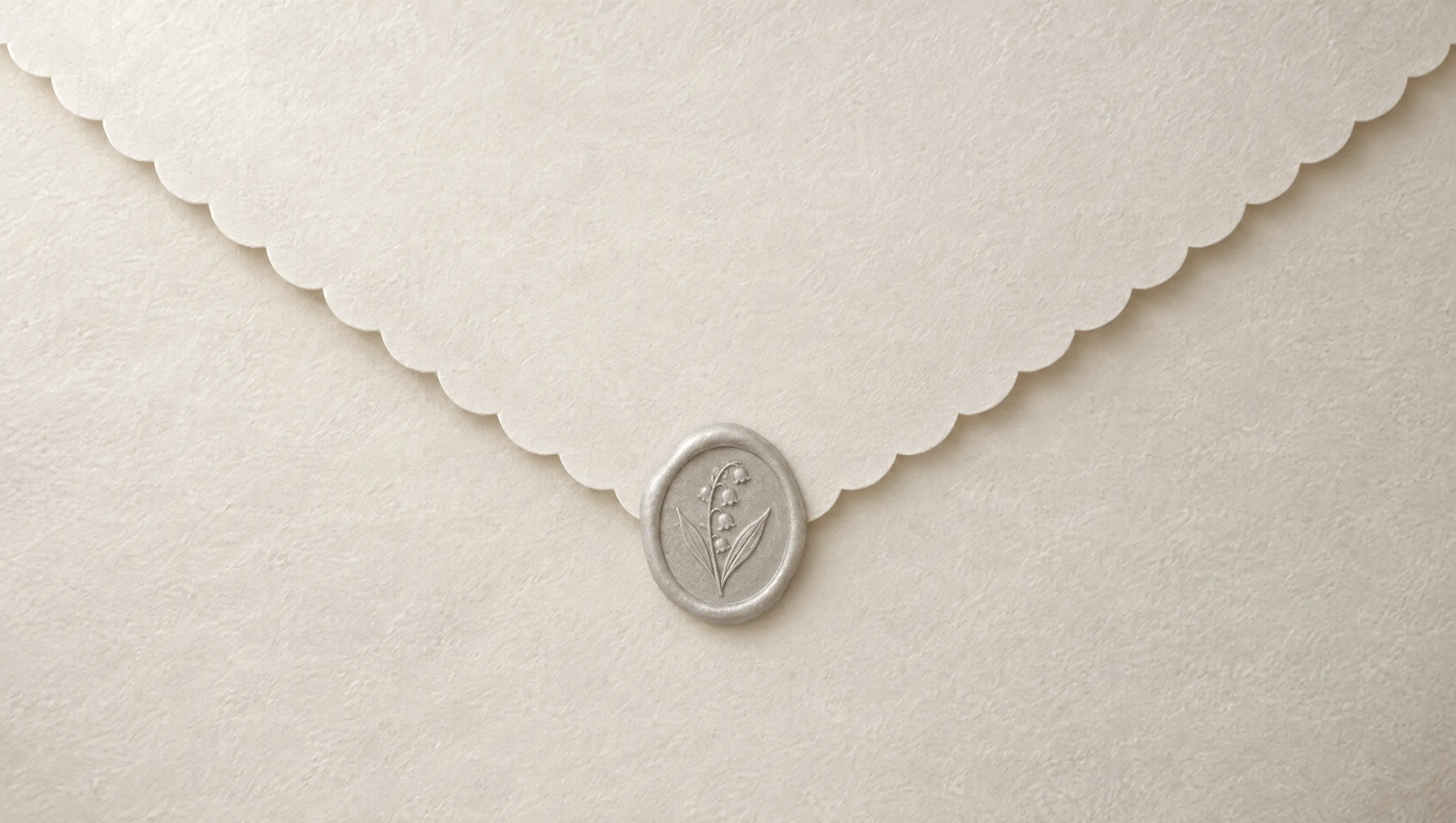 The back of a pearl-white envelope with a scalloped flap, sealed with pale silver wax