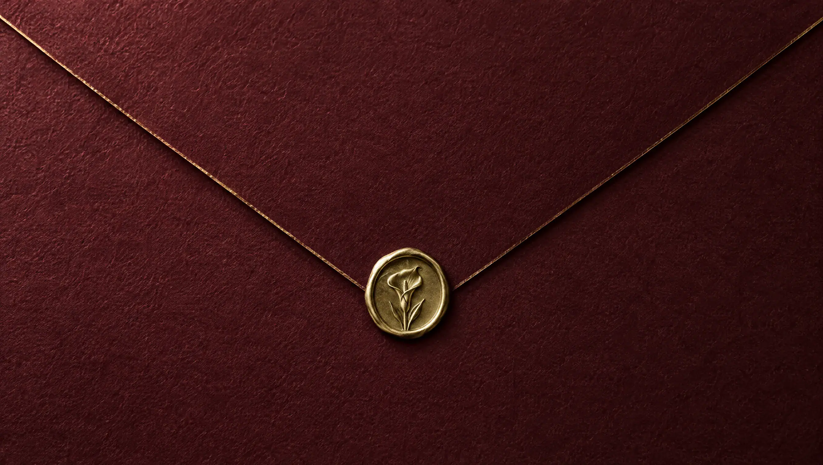 The back of a deep merlot-red envelope with a fine gold line along its flap, sealed with antique gold wax
